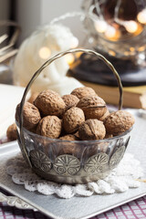 A vintage metal and glass vase with walnuts, in the background an antique clock, a marble figurine of a bear and an open book. Healthy food concept