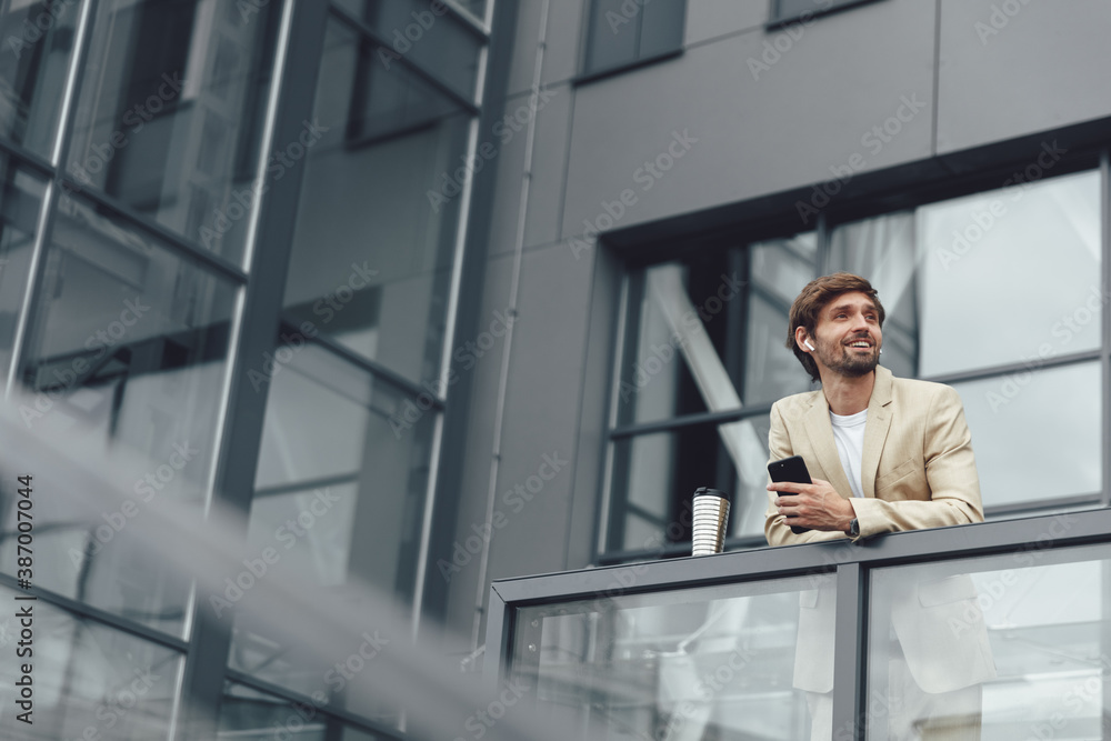 Wall mural businessman relaxing on balcony with coffee and smartphone