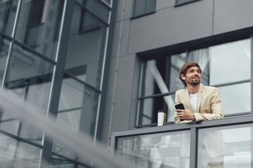 Businessman relaxing on balcony with coffee and smartphone
