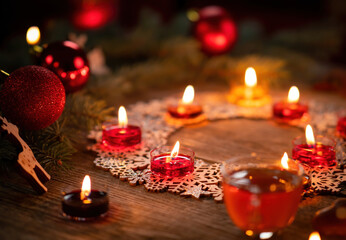 Winter ornamental decoration with burning candles on wooden rustic table. Mulled wine punch with gingerbread in foreground. Christmas holidays and New Year theme. Close-up