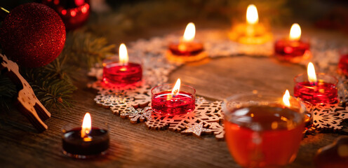 Winter ornamental decoration with burning candles on wooden rustic table. Mulled wine punch with gingerbread in foreground. Christmas holidays and New Year theme. Close-up