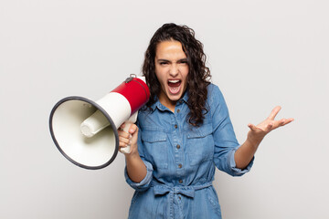 young hispanic woman looking angry, annoyed and frustrated screaming wtf or what’s wrong with you