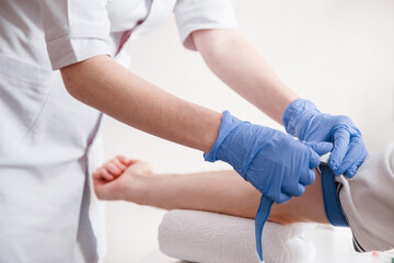 Nurse fastens the medical tourniquet on arm before taking blood test