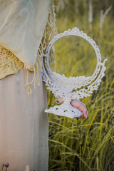 Fototapeta premium A Muslim woman stands on the field and holds a mirror in her hands. Muslim woman in beige hijab. Beauty, femininity.