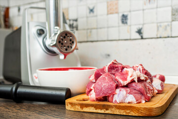 Meat grinder with fresh meat on a cutting board in kitchen interior. Machine for grinding meat into minced meat