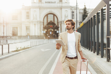 Successful businessman standing outdoors with digital tablet