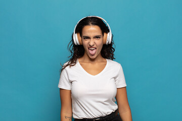 young hispanic woman with cheerful, carefree, rebellious attitude, joking and sticking tongue out,...