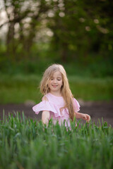 Fototapeta premium Little cute blonde girl on the field in the summer