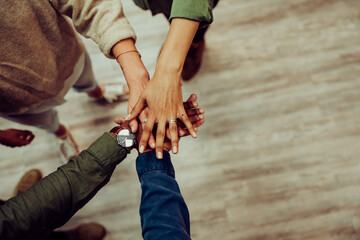 Diverse group of people gathering to stack hands showing unity and teamwork working together for big project presentation