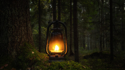 Old rusty oil lamp in dark autumn forest. Mystical scene with old kerosene lantern outdoor. Halloween concept.  - 387011483