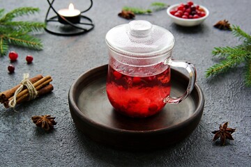 Hot drink, cranberry tea in a glass teapot or mug on a dark concrete background. Berry teas.