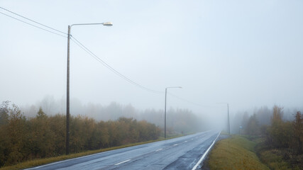 Quiet foggy road. Empty two lane road in a forest. Autumn season.