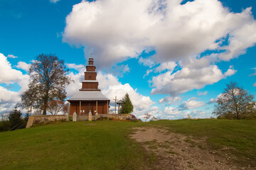 Old historical wooden countryside atholic cathedral building in Drysviaty village Belarus. The church on a hill with flowers and green grass in front of dramatic bright blue sky