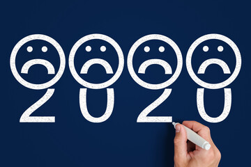 2020 and sad emoji. hand draws numbers 2020 next to sad emoticons
