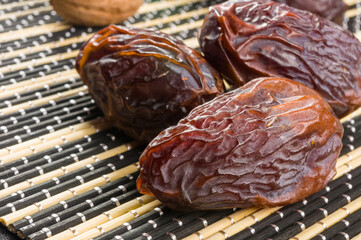 Big luxury dried date fruit on the bamboo mat, kurma ramadan kareem concept, close up.