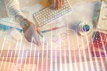 Multi exposure of man's hands typing over computer keyboard and forex graph hologram drawing. Top...
