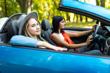 Two happy friends women in the cabriolet driving everywhere and looking for freedom and fun