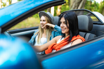 Two friends women on road Trip Driving In Convertible Car
