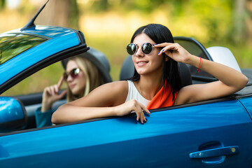 Young women wearing sunglasses in the white car. Little holiday trip of friends