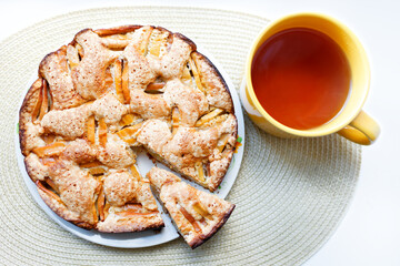 Appetizing charlotte with a cut piece. Round apple pie and tea.