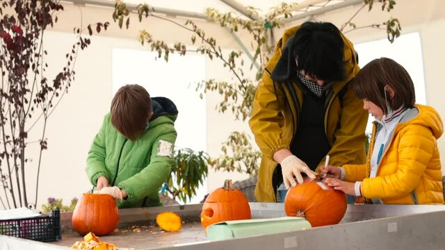 A teacher with children makes pumpkins for the holiday. They draw outlines for cutting in lesson in a forest school. Concentration of attention on activities.