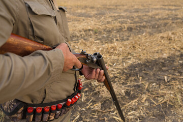 Close up of hunter loading shotgun, holds a gun and ammunition in his hand.