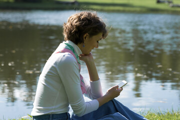 Young woman in the park speaks by mobile phone. Cute girl portrait in french style.