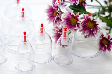 Jars for hijama on a white wooden background and pink harezantems. Bloodletting. Sunnah treatment. Islam. pink flowers