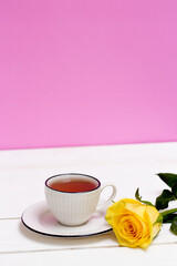Obraz na płótnie Canvas A cup of tea and oatmeal cookies. Yellow rose. Breakfast. Tea drinking. White wood background and pink wall.
