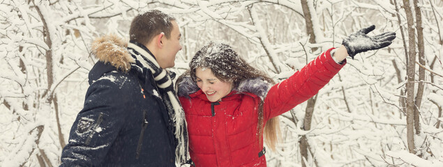 The guy and the girl have a rest in the winter woods. Husband and wife in the snow. Young couple walking in winter park