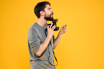 Male photographer with professional photo camera. Professional Creative approach studio yellow background