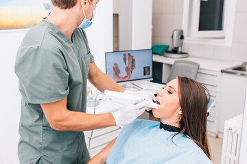 The dentist scans the patient's teeth with a 3d scanner. - 387027454