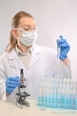 Microbiologist in biohazard protective clothing looking for biological tubes with covid-19 vaccine. Laboratory background. Close-up view. Healthcare and medical infection concept.