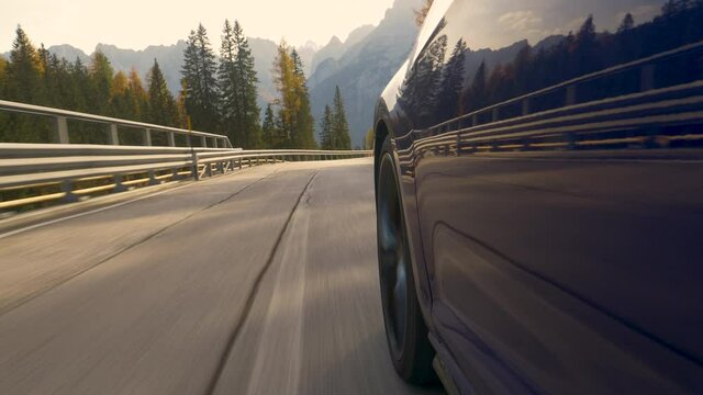 CLOSE UP: Sports car navigates a challenging serpentine route leading through the breathtaking Dolomites. Brand new blue car speeds down a scenic switchback road near the world famous Tre Cime.