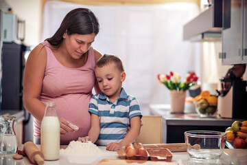 Obraz na płótnie Canvas Pregnant woman and son making cookies.