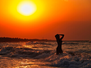 Young woman swimming in the sea at sunset