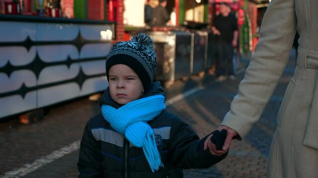 Mother with Child at Christmas Market Walking and Looking Around. Winter Holidays. Evening City Street. 2x Slow motion 60 fps 4K