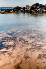 A rock formation in the beach at low tide with sky reflections