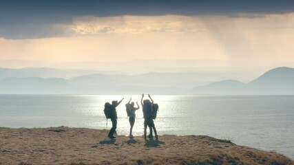 The four travelers have fun on the mountain top on seascape background