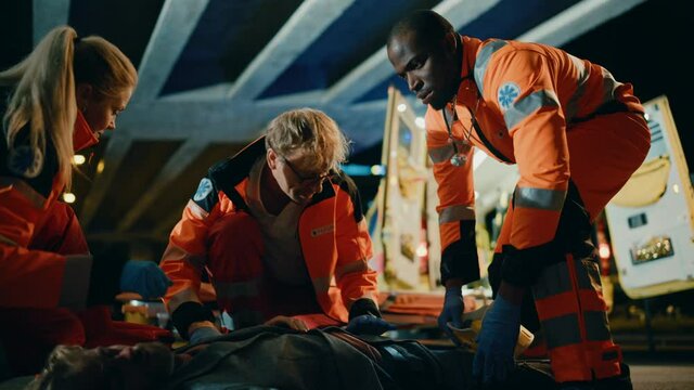Team of EMS Paramedics Quickly Jump Out from Ambulance Vehicle. Female Doctor Brings First Aid Kit. Emergency Care Assistants Arrived on the Scene of a Traffic Accident on a Street at Night.