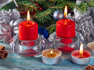 Horizontal background of the New year.Candles burn on glass candlesticks, against the background of pine branches and Christmas decorations.
