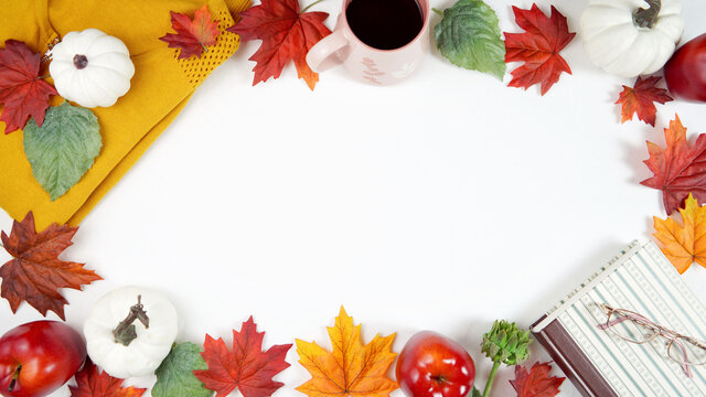 Autumn Fall Thanksgiving relaxation hygge theme flatlay with gold sweater, reading glasses and book and scattered maple leaves background. Top down creative composition blog hero header. Copy space.