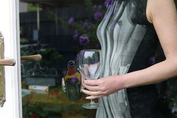 Mature woman holding a glass of red wine as seen through glass door.