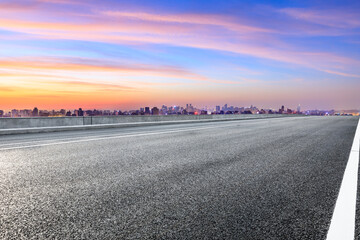 Empty asphalt road and city skyline with buildings in Hangzhou at sunrise.