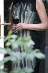 Mature woman holding a glass of red wine as seen through glass door.