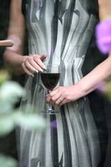 Mature woman holding a glass of red wine as seen through glass door.