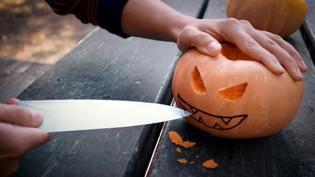 Woman preparing an evil pumpkin for Halloween with the knife