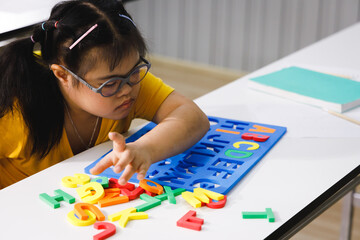 Girl with Down's syndrome play alphabet puzzle toy.