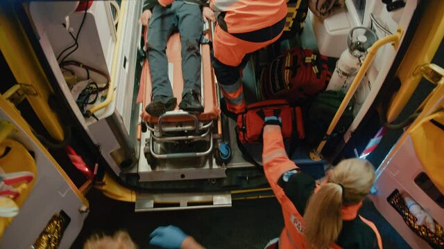 Aerial Footage of a Team of EMS Paramedics Providing Medical Help to Injured Patient and Get Him in Ambulance on a Stretcher. Doctors Arrived on the Scene of a Traffic Accident on a Street.