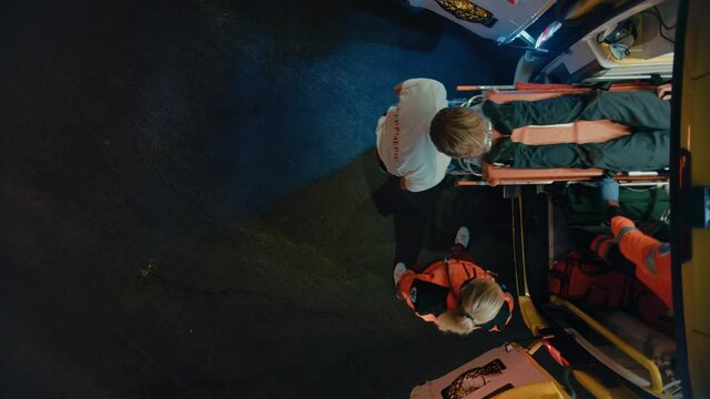 Footage from Above of a Team of EMS Paramedics Bringing Injured Patient to Hospital and Get Him Out of Ambulance on a Stretcher. Emergency Care Assistants Help Young Man to Stay Alive After Accident.